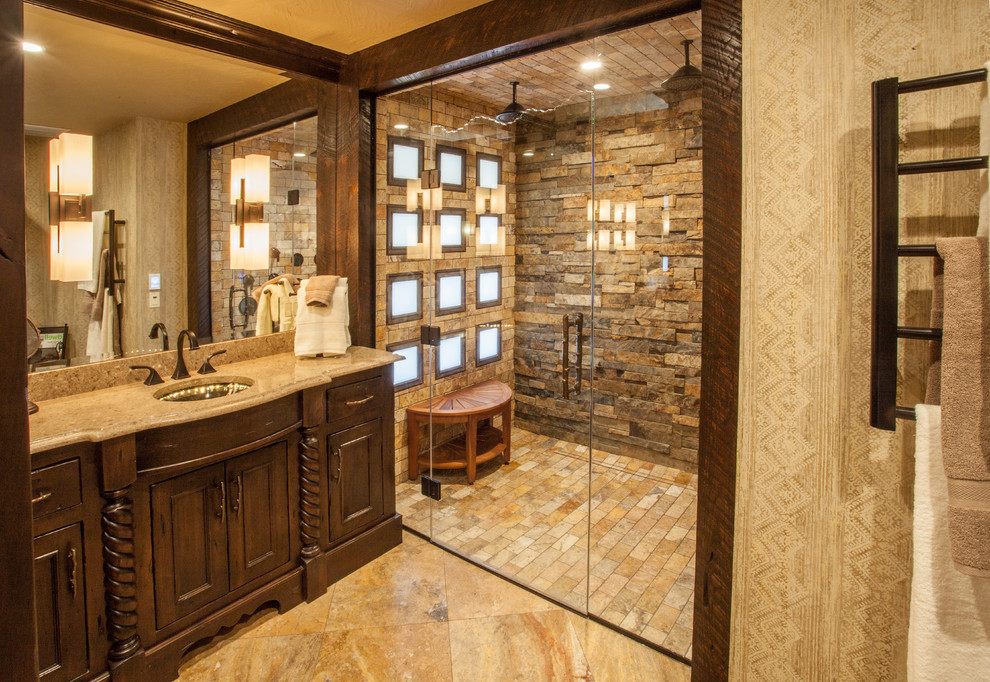 Mid-sized mountain style master beige tile and stone tile travertine floor walk-in shower photo with recessed-panel cabinets, dark wood cabinets, a two-piece toilet, beige walls, an undermount sink and quartz countertops