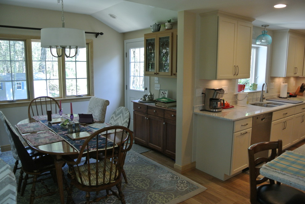 Inspiration for a transitional l-shaped medium tone wood floor eat-in kitchen remodel in Boston with an undermount sink, shaker cabinets, white cabinets, recycled glass countertops, white backsplash, subway tile backsplash, stainless steel appliances, a peninsula and white countertops