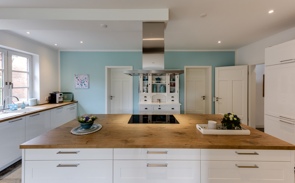 Foto på ett stort lantligt kök, med en rustik diskho, luckor med profilerade fronter, vita skåp, träbänkskiva, rostfria vitvaror, flerfärgat golv, blått stänkskydd, stänkskydd i glaskakel, klinkergolv i keramik och en köksö