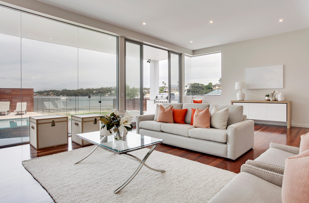 This is an example of a contemporary living room in Sydney with beige walls and dark hardwood floors.