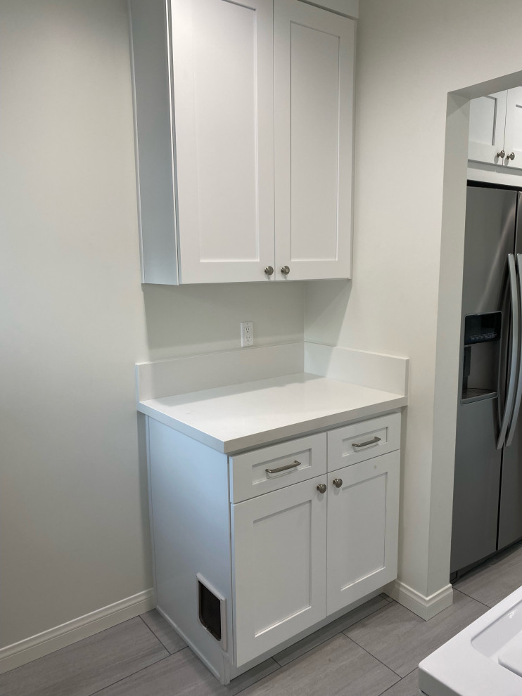 Example of a small minimalist u-shaped eat-in kitchen design in Los Angeles with flat-panel cabinets, white cabinets and white countertops
