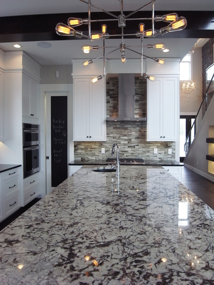 Transitional open concept kitchen photo with white cabinets, stainless steel appliances, an island and flat-panel cabinets