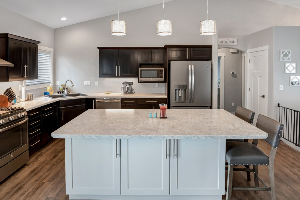 Open concept kitchen - large transitional l-shaped medium tone wood floor open concept kitchen idea with a double-bowl sink, shaker cabinets, dark wood cabinets, quartzite countertops, stainless steel appliances and an island