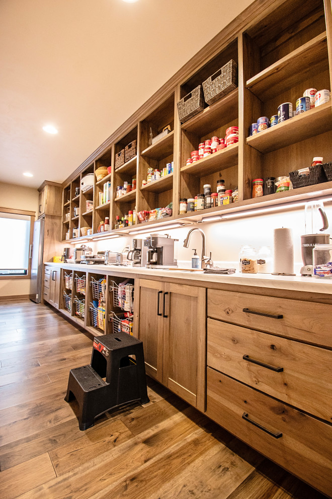 Large mountain style single-wall medium tone wood floor and multicolored floor enclosed kitchen photo with a drop-in sink, flat-panel cabinets, medium tone wood cabinets, quartzite countertops, stainless steel appliances and multicolored countertops
