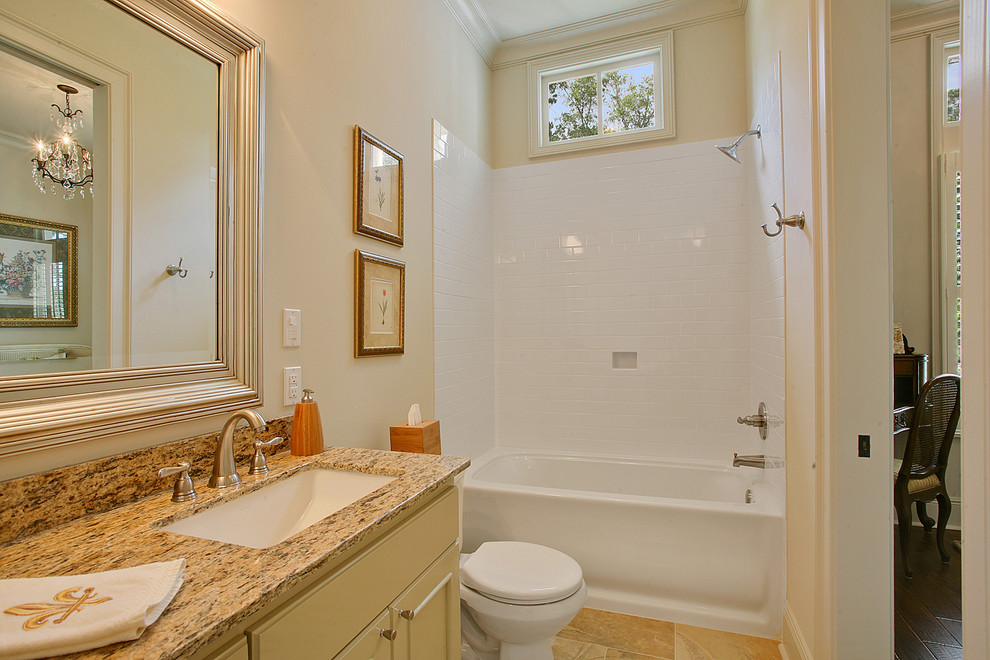 Inspiration for a traditional bathroom in New Orleans with shaker cabinets, yellow cabinets, a shower/bathtub combo, a two-piece toilet, yellow tile, porcelain tile, beige walls, porcelain floors, an undermount sink and granite benchtops.