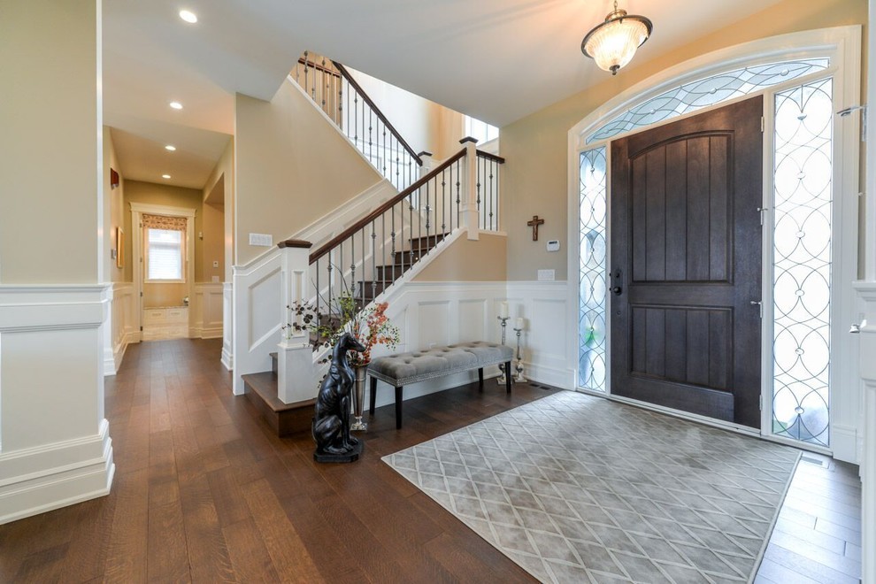 This is an example of a mid-sized transitional foyer in Calgary with beige walls, medium hardwood floors, a single front door and a dark wood front door.