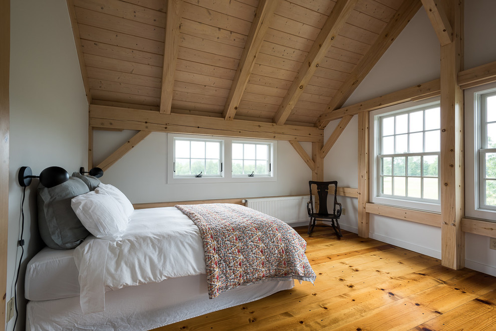 Photo of a mid-sized country master bedroom in New York with white walls, light hardwood floors and yellow floor.