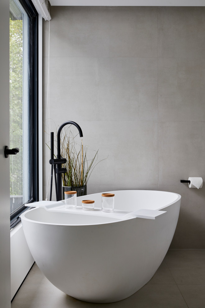Contemporary bathroom in London with a freestanding tub, grey walls and grey floor.