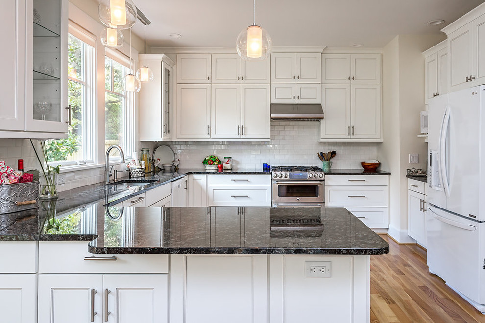 Design ideas for a mid-sized traditional u-shaped eat-in kitchen in Raleigh with a single-bowl sink, flat-panel cabinets, white cabinets, granite benchtops, yellow splashback, ceramic splashback, stainless steel appliances, medium hardwood floors and a peninsula.