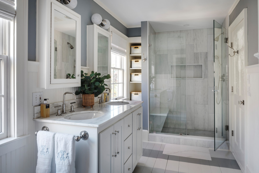This is an example of a beach style 3/4 bathroom in Boston with shaker cabinets, white cabinets, an alcove shower, grey walls, an undermount sink, marble benchtops, a hinged shower door, multi-coloured benchtops, a double vanity and a built-in vanity.