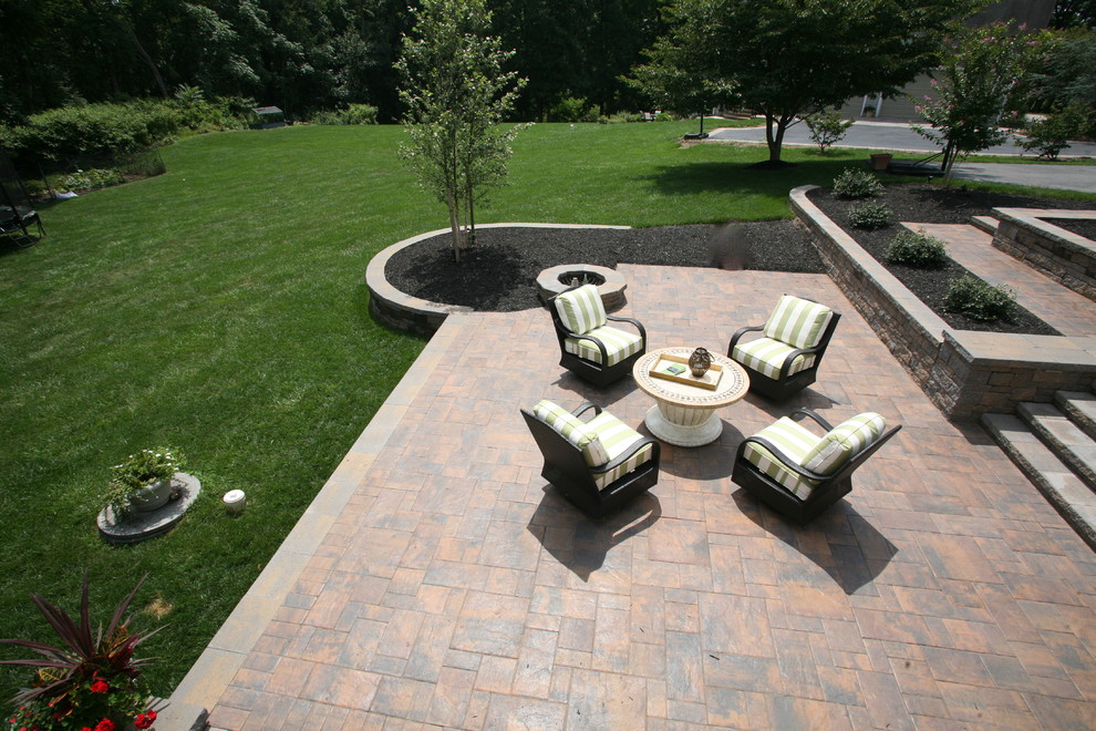 This is an example of a mid-sized traditional backyard patio in Baltimore with a fire feature, concrete pavers and no cover.