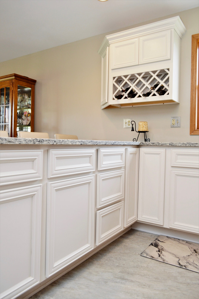 Example of a mid-sized transitional l-shaped eat-in kitchen design in Chicago with an undermount sink, recessed-panel cabinets, white cabinets, quartzite countertops, stainless steel appliances, a peninsula and gray countertops