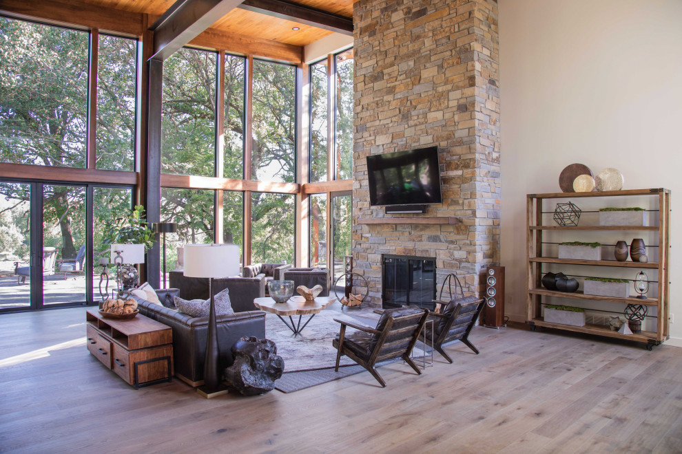 Large modern open concept living room in Other with white walls, medium hardwood floors, a standard fireplace, a stone fireplace surround, a wall-mounted tv and brown floor.