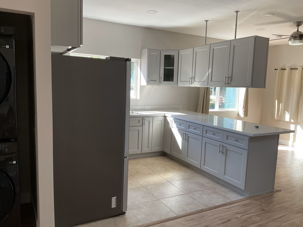 Idéer för att renovera ett mellanstort vintage grå grått kök, med luckor med infälld panel, grå skåp, klinkergolv i keramik, beiget golv, en rustik diskho, bänkskiva i kvartsit, vitt stänkskydd, rostfria vitvaror och en halv köksö