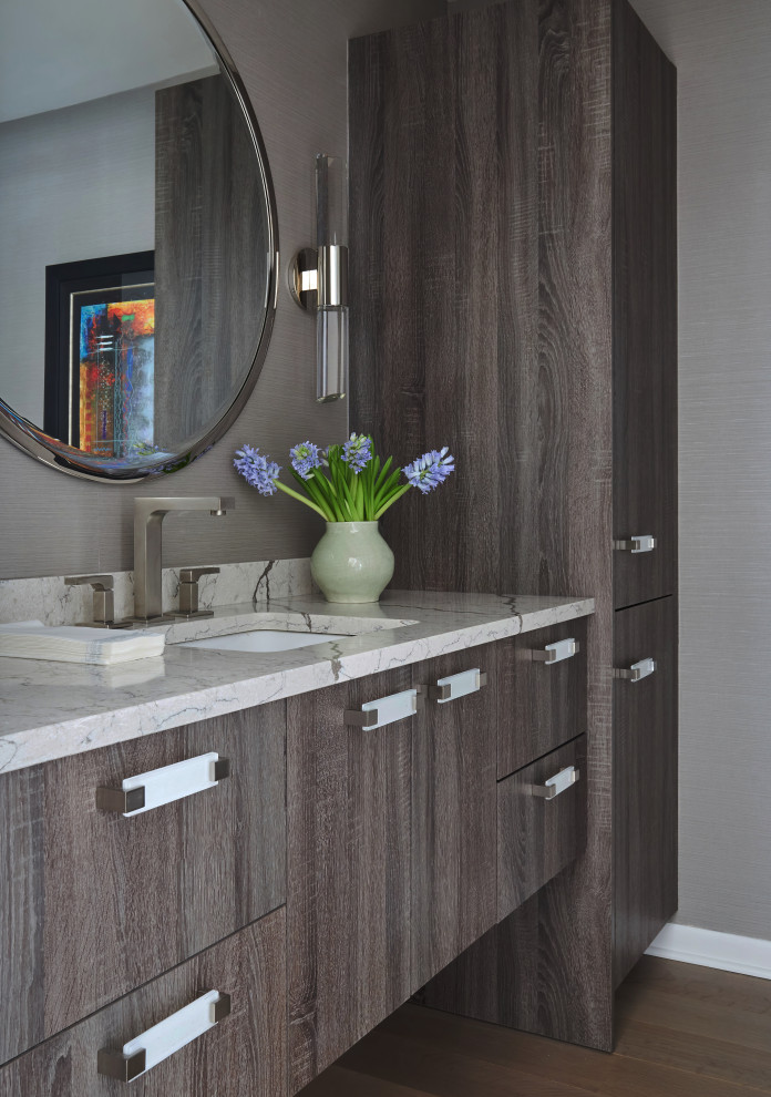 Large contemporary cloakroom in Chicago with flat-panel cabinets, brown cabinets, a one-piece toilet, grey walls, medium hardwood flooring, a submerged sink, engineered stone worktops, brown floors, white worktops, a floating vanity unit and wallpapered walls.