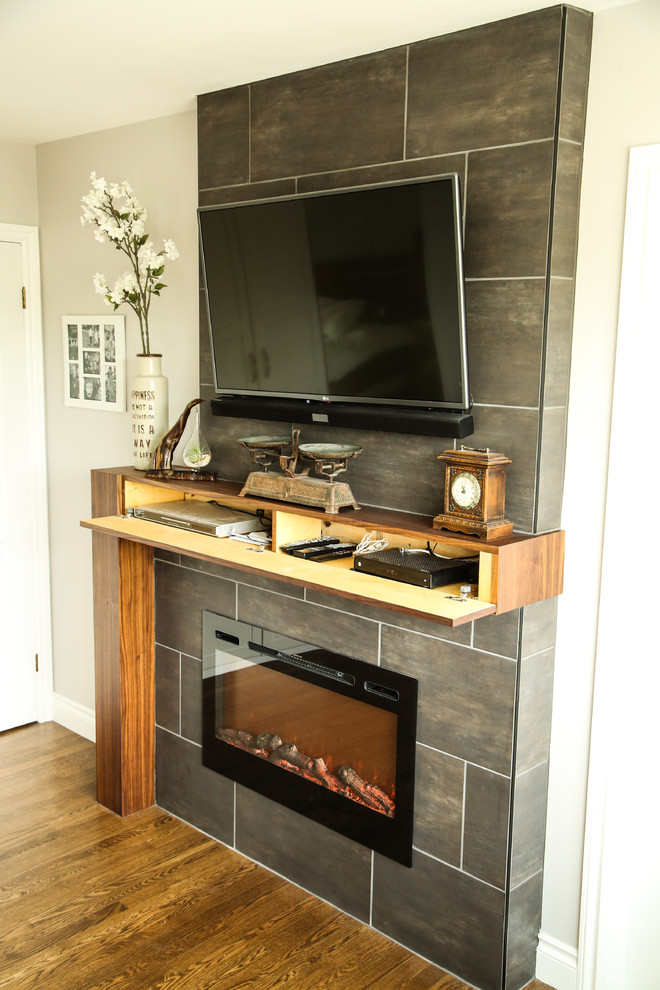 Inspiration for a mid-sized transitional master medium tone wood floor and brown floor bedroom remodel in Edmonton with gray walls, a ribbon fireplace and a tile fireplace