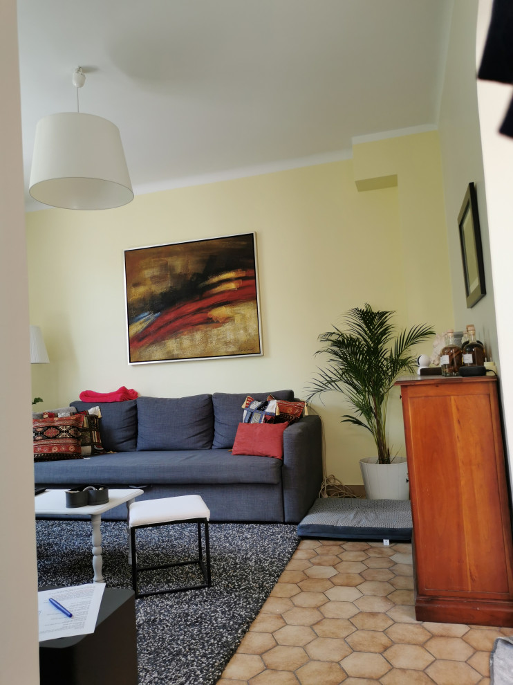 This is an example of a small modern open concept living room in Nantes with beige walls, terra-cotta floors, a freestanding tv and beige floor.