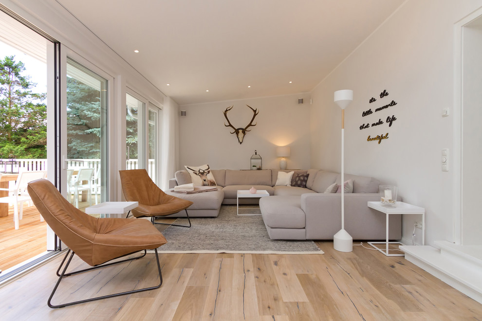 Photo of a mid-sized contemporary enclosed living room in Berlin with white walls, light hardwood floors and brown floor.