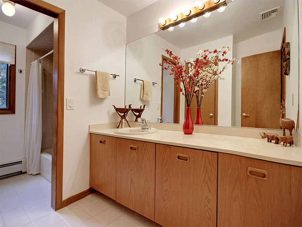 Mid-sized contemporary 3/4 bathroom in New York with a drop-in sink, flat-panel cabinets, medium wood cabinets, laminate benchtops, a drop-in tub, a shower/bathtub combo, a two-piece toilet, beige tile, ceramic tile, white walls and ceramic floors.