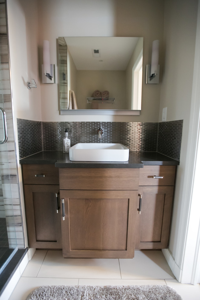 This is an example of a mid-sized transitional kids bathroom in Indianapolis with black cabinets, ceramic floors, a hinged shower door, recessed-panel cabinets, black tile, metal tile, beige walls, a vessel sink, engineered quartz benchtops, white floor and black benchtops.