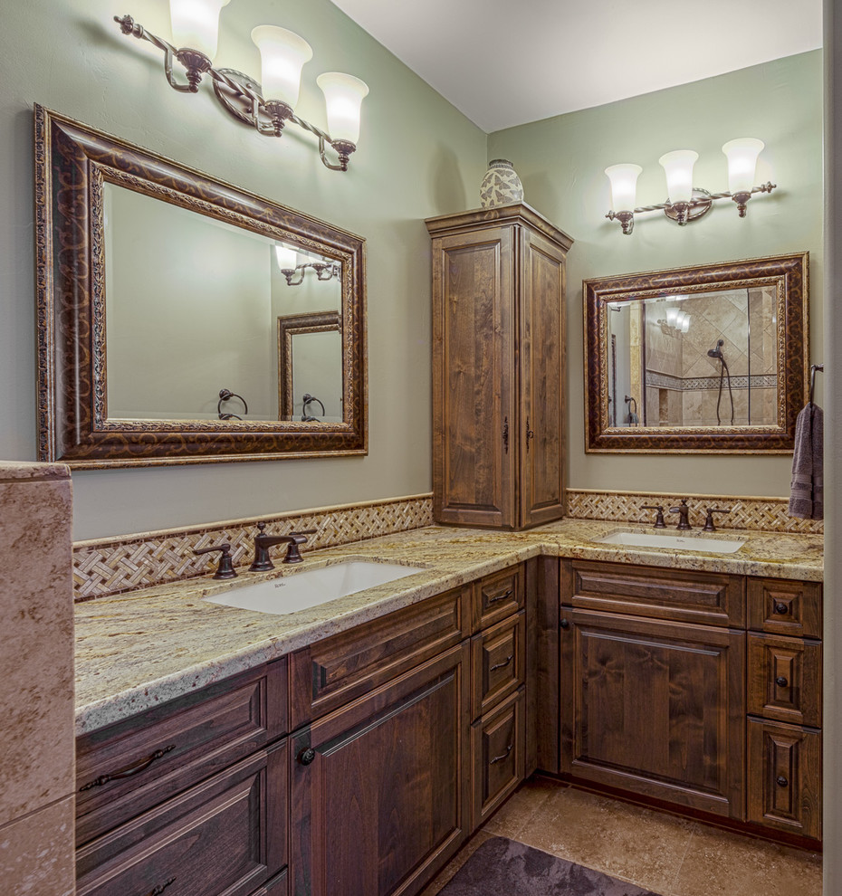 Design ideas for a mid-sized mediterranean master bathroom in Phoenix with raised-panel cabinets, an open shower, a one-piece toilet, beige tile, stone tile, green walls, ceramic floors, granite benchtops, dark wood cabinets, an undermount sink and beige floor.