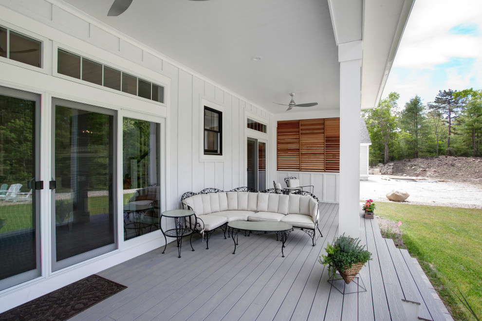 Foto på en stor lantlig veranda på baksidan av huset, med trädäck och takförlängning
