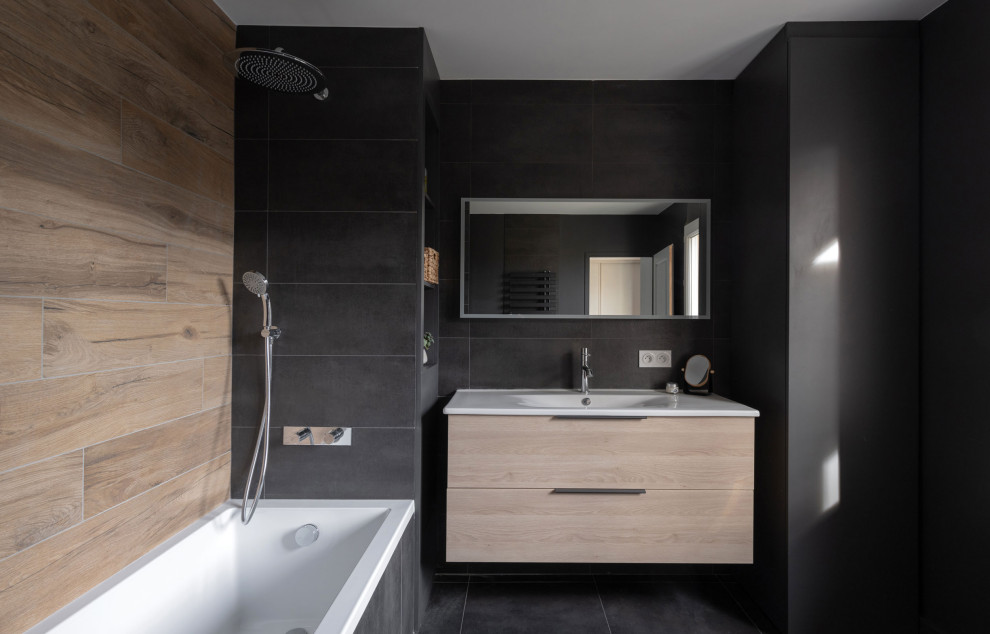 Mid-sized modern master bathroom in Lyon with beaded inset cabinets, beige cabinets, a floating vanity, an undermount tub, a shower/bathtub combo, a wall-mount toilet, multi-coloured tile, wood-look tile, black walls, slate floors, solid surface benchtops, black floor, white benchtops, a single vanity and wood walls.