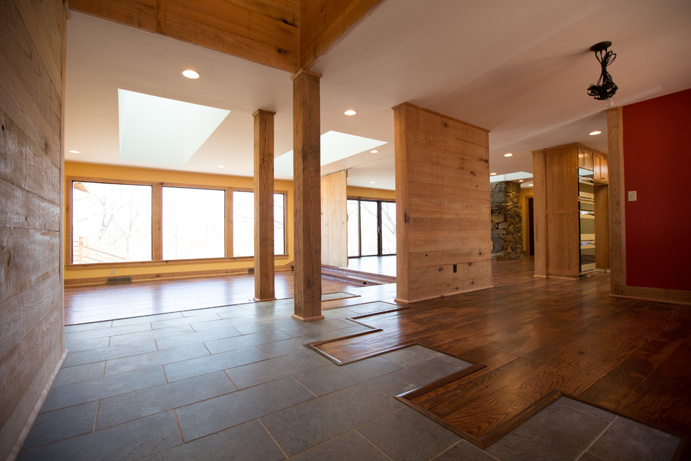 Large mountain style formal and open concept dark wood floor home design photo with orange walls, a standard fireplace, a stone fireplace and no tv