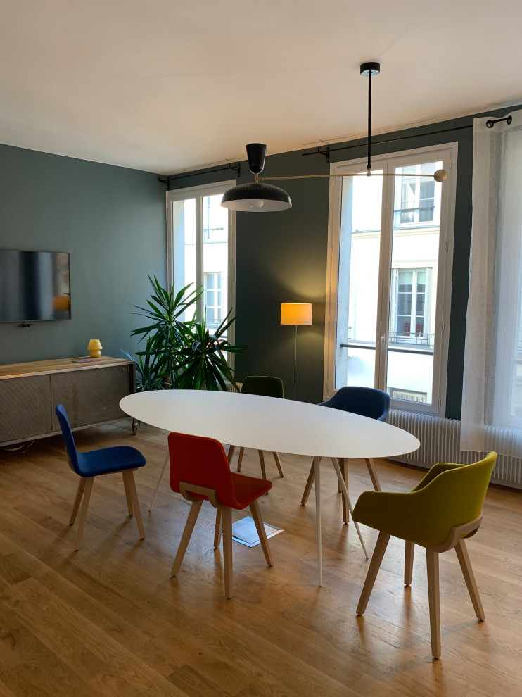 This is an example of a large industrial open concept family room in Paris with blue walls, medium hardwood floors, a wall-mounted tv and brown floor.