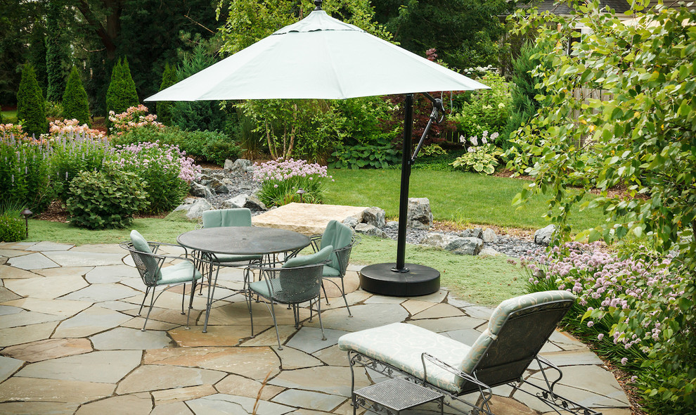 Photo of a mid-sized eclectic backyard patio in Milwaukee with natural stone pavers.