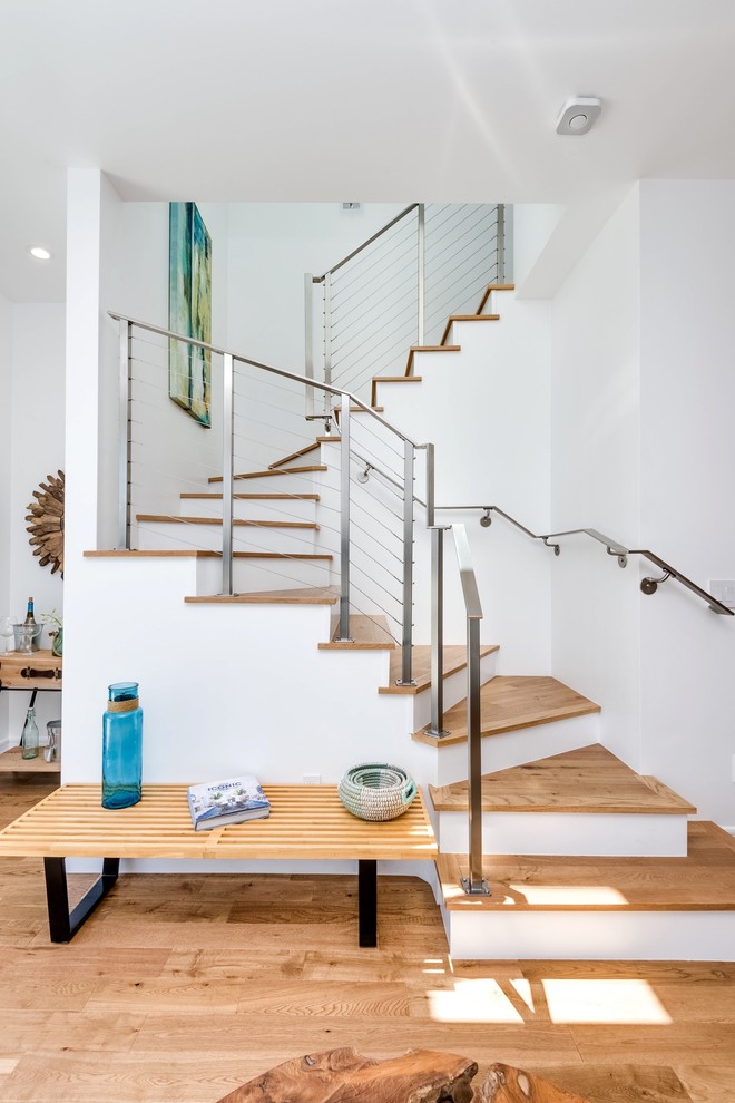 This is an example of a beach style wood curved staircase in Los Angeles with painted wood risers.