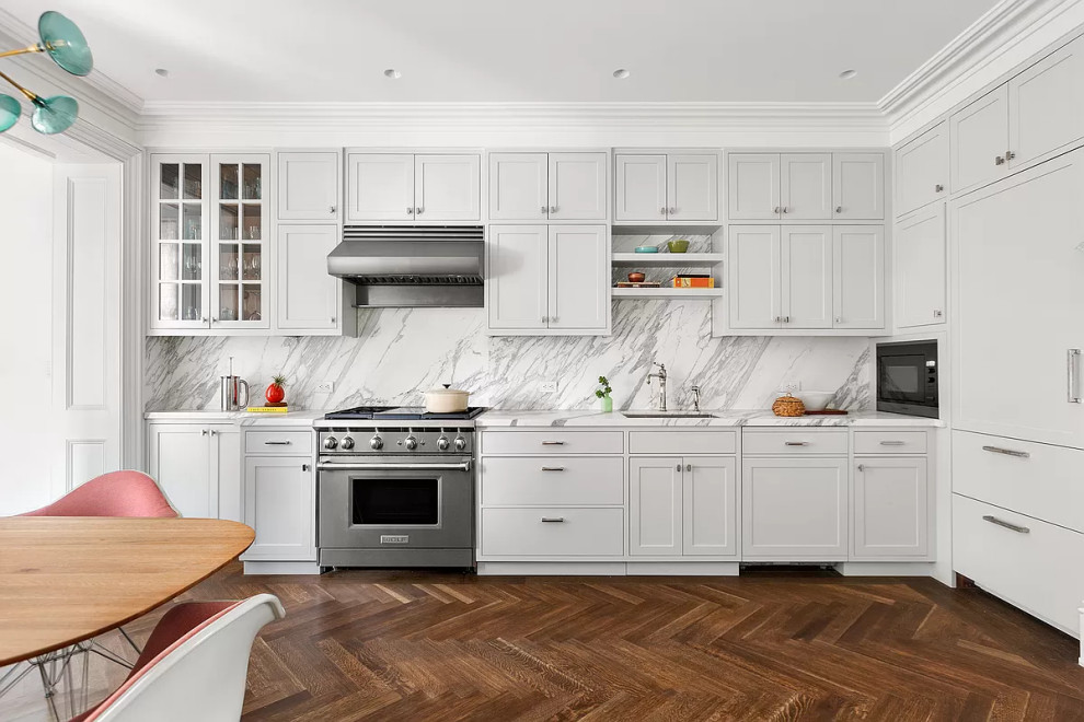 Bild på ett mellanstort retro vit vitt kök, med en enkel diskho, skåp i shakerstil, grå skåp, marmorbänkskiva, vitt stänkskydd, stänkskydd i marmor, integrerade vitvaror, mellanmörkt trägolv och brunt golv