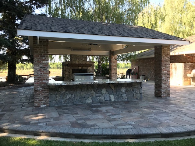 This is an example of a mid-sized traditional backyard patio in Sacramento with an outdoor kitchen, concrete pavers and a roof extension.