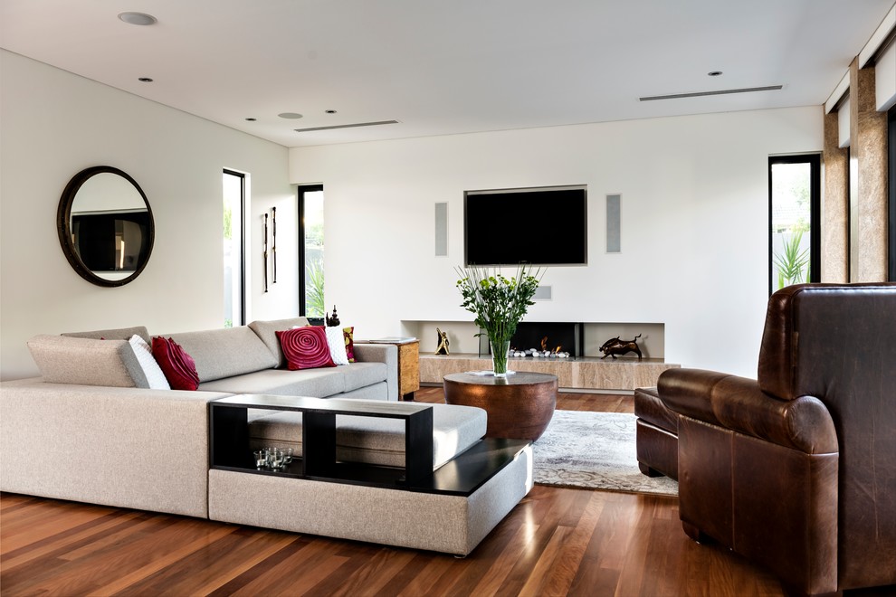 This is an example of a large contemporary open concept living room in Perth with white walls, medium hardwood floors, a plaster fireplace surround, brown floor, a ribbon fireplace and a wall-mounted tv.