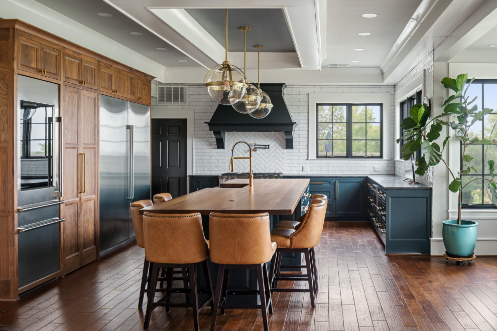 Kitchen - transitional u-shaped dark wood floor, brown floor and tray ceiling kitchen idea in Kansas City with a farmhouse sink, shaker cabinets, blue cabinets, white backsplash, subway tile backsplash, stainless steel appliances, an island and gray countertops