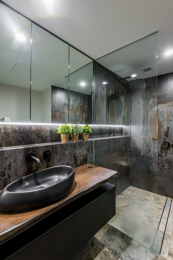 Mid-sized contemporary kids bathroom in Brisbane with furniture-like cabinets, dark wood cabinets, an open shower, a one-piece toilet, gray tile, porcelain tile, multi-coloured walls, travertine floors, a vessel sink, wood benchtops, beige floor and an open shower.