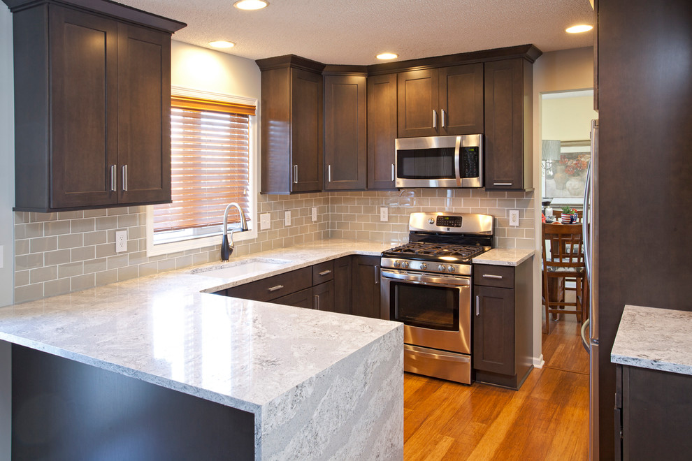 Mid-sized transitional u-shaped medium tone wood floor eat-in kitchen photo in Minneapolis with an undermount sink, flat-panel cabinets, dark wood cabinets, gray backsplash, glass tile backsplash, stainless steel appliances and a peninsula