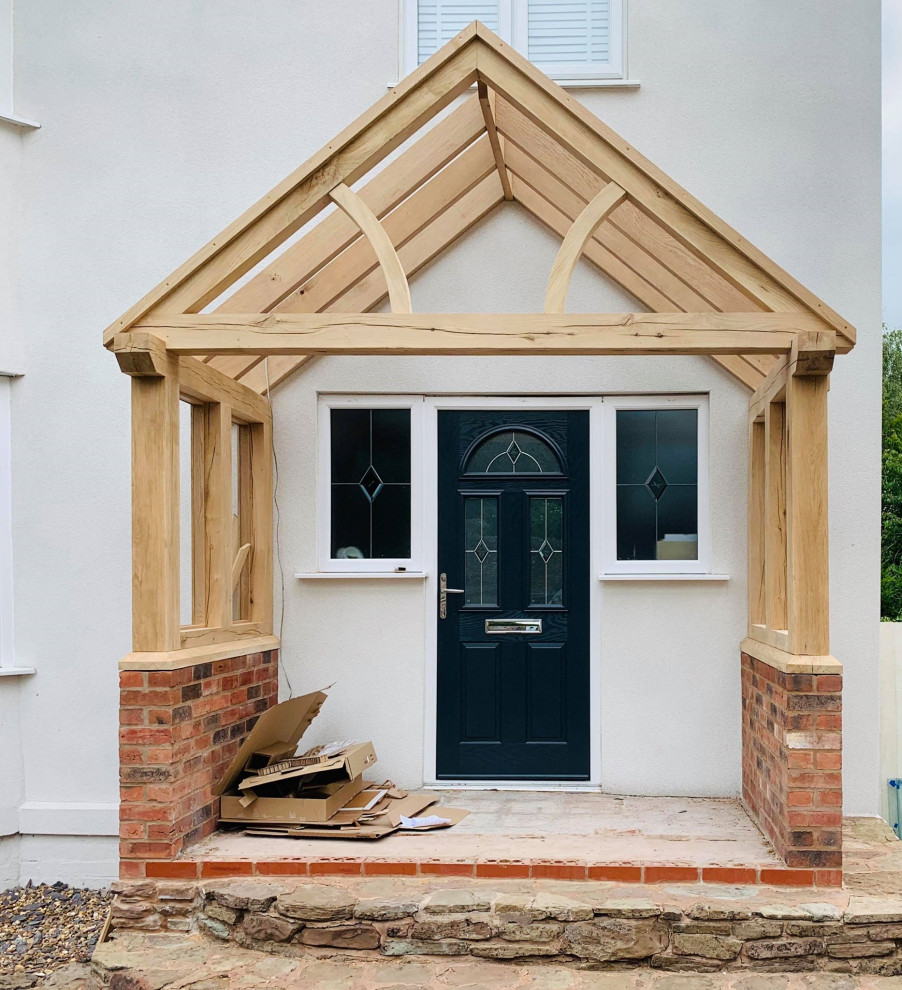 This is an example of a large front door in West Midlands with white walls, brick floors, a single front door, exposed beam and brick walls.