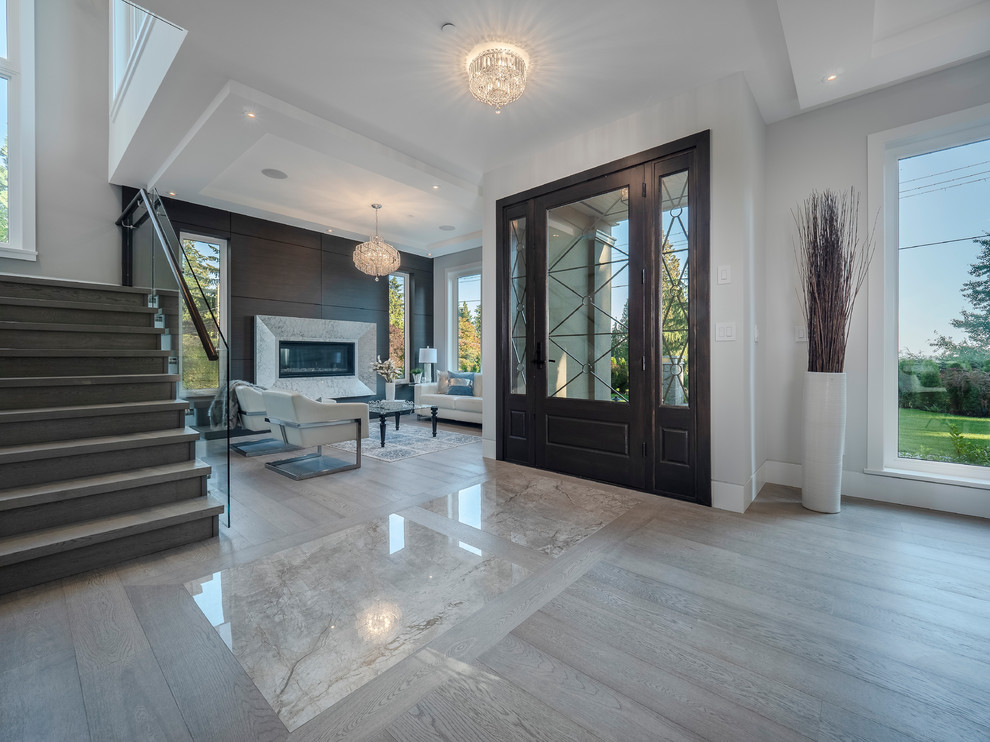 Inspiration for a large contemporary front door in Vancouver with grey walls, light hardwood floors, a single front door, a glass front door and grey floor.