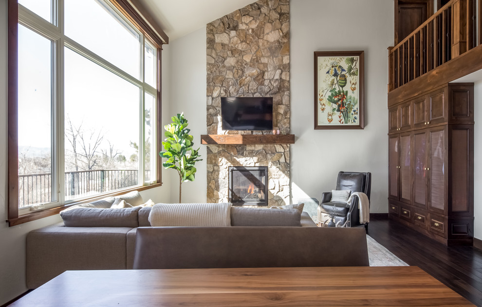 Example of a mid-sized mountain style open concept dark wood floor and brown floor living room design in Denver with a standard fireplace, a stone fireplace, a wall-mounted tv and white walls