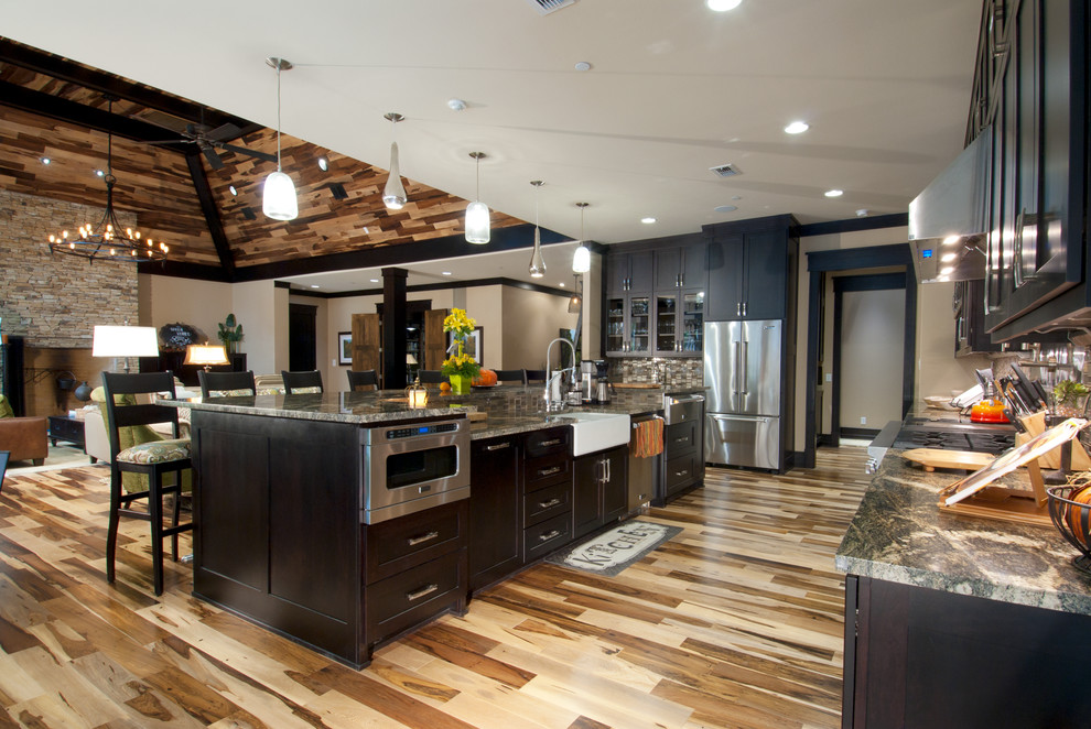 Arts and crafts galley eat-in kitchen in Dallas with a farmhouse sink, shaker cabinets, dark wood cabinets, granite benchtops, multi-coloured splashback, glass sheet splashback, stainless steel appliances, light hardwood floors and with island.