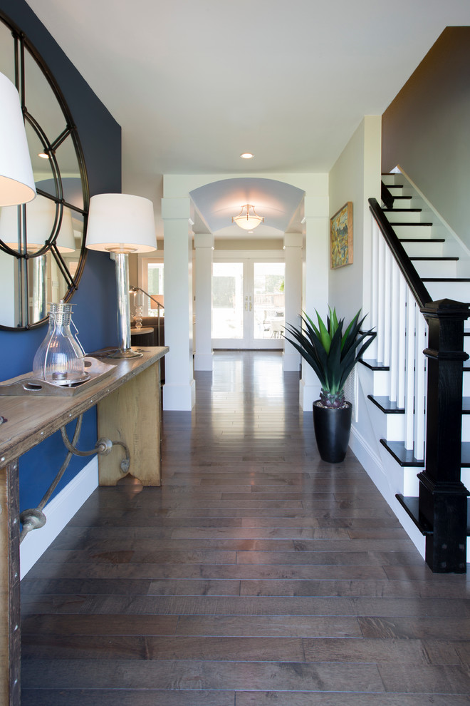 Mid-sized trendy dark wood floor and brown floor foyer photo with blue walls