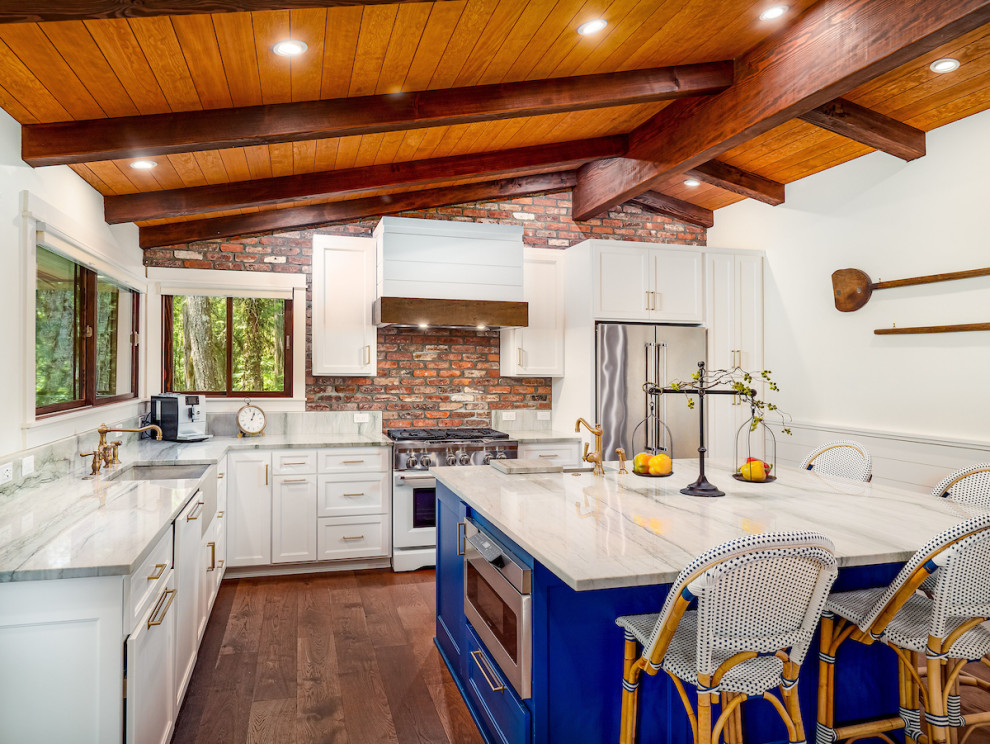 Mid-sized mountain style l-shaped vinyl floor, brown floor and exposed beam eat-in kitchen photo with an island, an undermount sink, recessed-panel cabinets, white cabinets, quartzite countertops, brown backsplash, brick backsplash, stainless steel appliances and white countertops