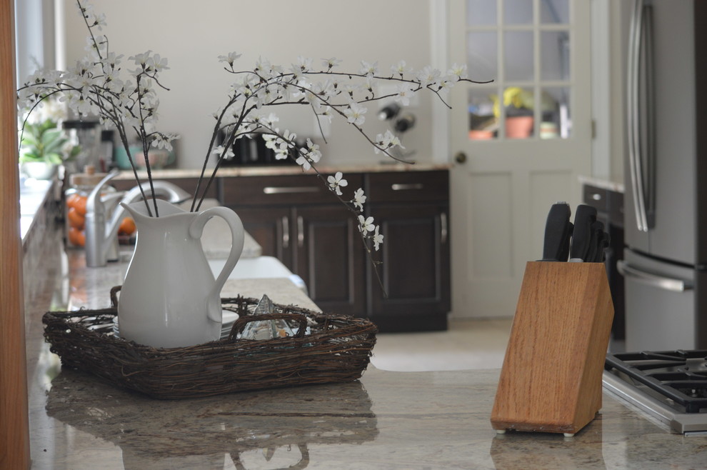 Large transitional l-shaped porcelain tile and beige floor eat-in kitchen photo with a farmhouse sink, raised-panel cabinets, brown cabinets, granite countertops, white backsplash, ceramic backsplash, stainless steel appliances and a peninsula