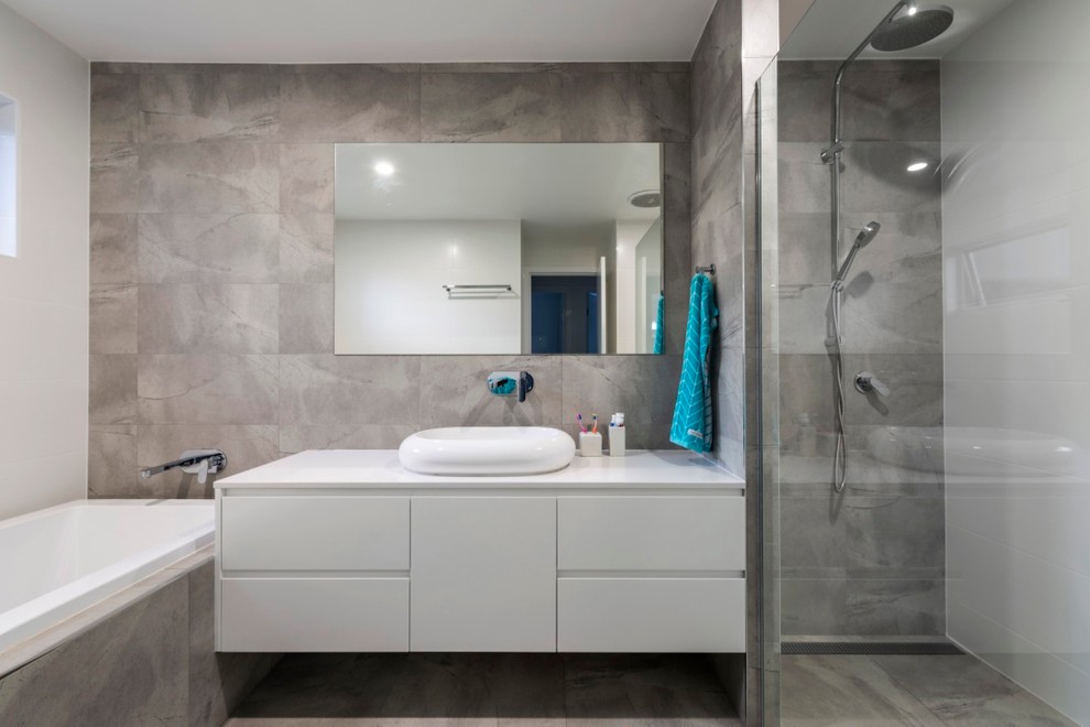 Inspiration for a mid-sized contemporary master bathroom in Gold Coast - Tweed with white cabinets, a drop-in tub, an open shower, a one-piece toilet, gray tile, ceramic tile, white walls, ceramic floors, a vessel sink, wood benchtops, grey floor and an open shower.