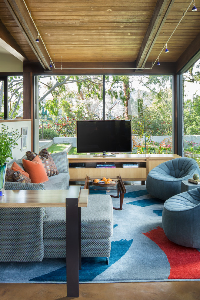 This is an example of a large contemporary open concept family room in Los Angeles with a freestanding tv, concrete floors and blue floor.