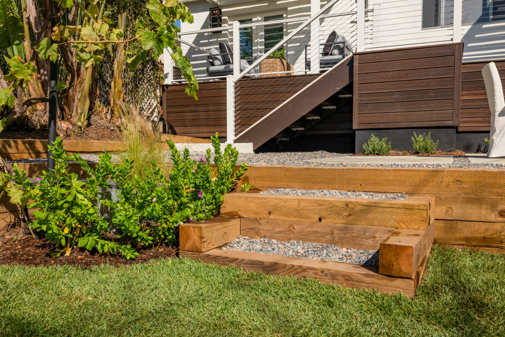 Photo of a small beach style backyard and ground level deck in Other with with skirting, a pergola and cable railing.