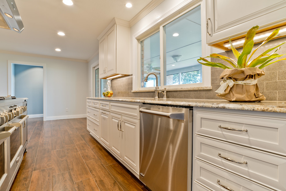 Inspiration for a large transitional galley porcelain tile eat-in kitchen remodel in Miami with an undermount sink, raised-panel cabinets, white cabinets, granite countertops, gray backsplash, porcelain backsplash, stainless steel appliances and an island