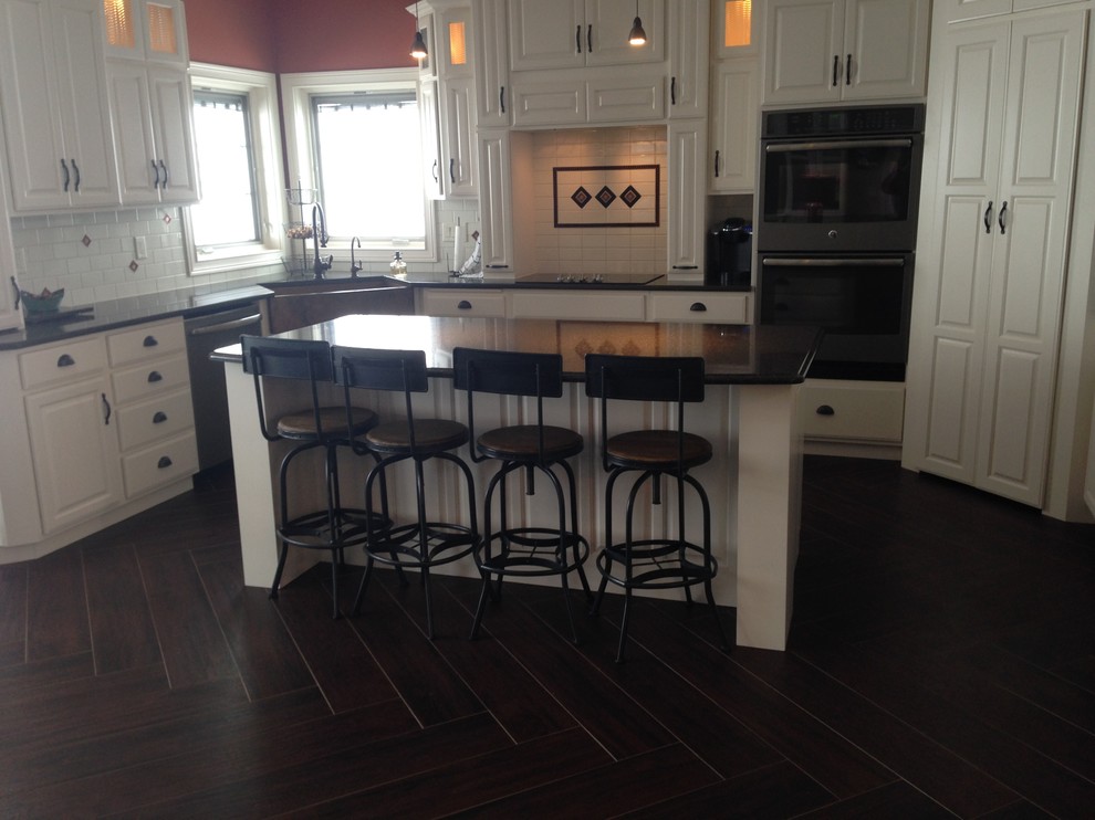 Inspiration for a mid-sized timeless l-shaped dark wood floor and black floor open concept kitchen remodel with a farmhouse sink, raised-panel cabinets, white cabinets, quartz countertops, white backsplash, ceramic backsplash, stainless steel appliances, an island and black countertops