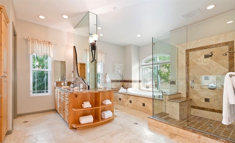 Design ideas for a large mediterranean master bathroom in San Diego with raised-panel cabinets, light wood cabinets, a drop-in tub, a double shower, a one-piece toilet, beige tile, ceramic tile, white walls, porcelain floors, a drop-in sink, beige floor and a hinged shower door.